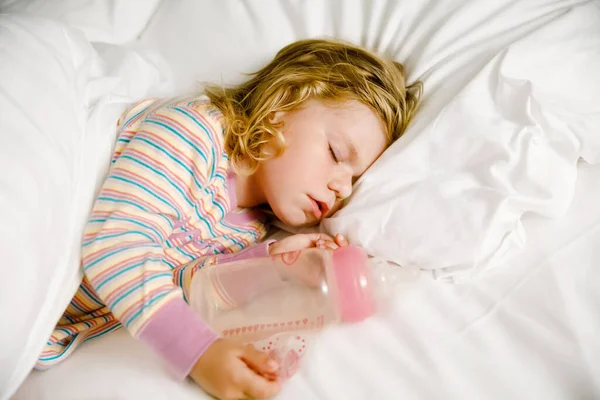 Linda niña pequeña durmiendo en la cama grande de los padres. Niño adorable soñando en la cama del hotel en vacaciones familiares o en casa. — Foto de Stock