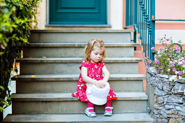 Portrait of beautiful little gorgeus lovely toddler girl in pink summer look clothes, fashion dress, knee socks and hat. Happy healthy baby child posing infront of colorful house. — Stock Photo, Image