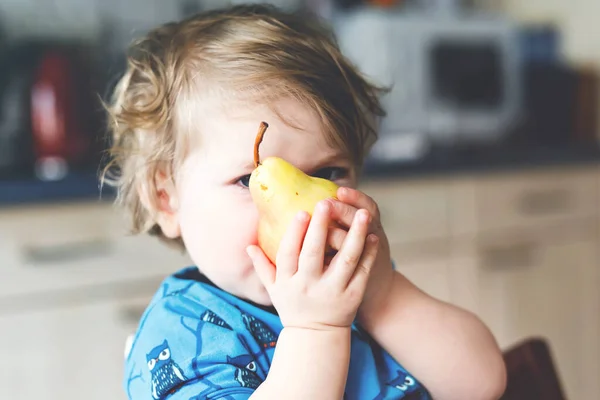 かわいい愛らしい幼児の女の子は新鮮な梨を食べています。果物を持つ1年の空腹幸せな赤ちゃん. — ストック写真