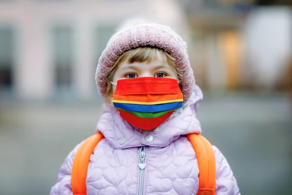 Kleines Mädchen mit medizinischer Maske auf dem Weg zum Kindergarten, Kindergarten oder Kindergarten. Kind mit Rucksacktasche an kalten Tagen mit warmer Kleidung. Sperrung und Quarantäne während der Coronapandemie — Stockfoto