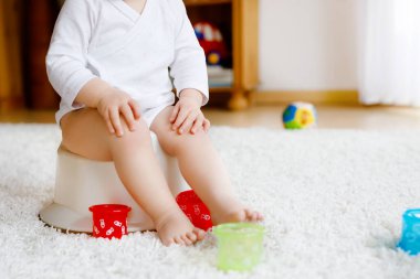 Lazımlığın üzerinde oturan küçük, tatlı, yaşlı, küçük kız bebek. Çocuk eğitim oyuncağı ve tuvalet eğitimi konseptiyle oynuyor. Bebek öğrenme, gelişme adımları. Yüzü yok, tanınmayan biri..