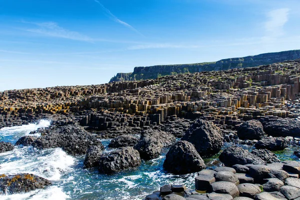 Kuzey İrlanda, Antrim ilçesinde yaz mevsiminde mavi gökyüzü olan Giants Geçidi 'nin manzarası. UNESCO mirası. Eski bir volkanik yarığın sonucu olarak bazalt sütunların oluşturduğu bir alan. — Stok fotoğraf