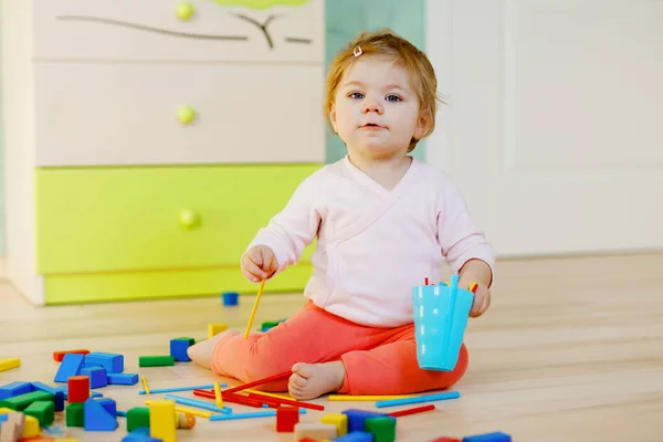 Cute little baby girl playing with educational toys. Happy healthy child having fun with colorful different wooden blocks at home or nursery. Baby crawling and learning colors and forms, indoors — Stock Photo, Image