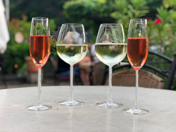 Cuatro copas con vino. Dos copas de vino rosa y vino blanco en la mesa en el restaurante al aire libre en verano. —  Fotos de Stock