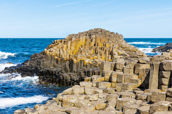 Landscape of Giants Causeway trail with a blue sky in summer in Northern Ireland, County Antrim. UNESCO heritage. It is an area of basalt columns, the result of an ancient volcanic fissure eruption