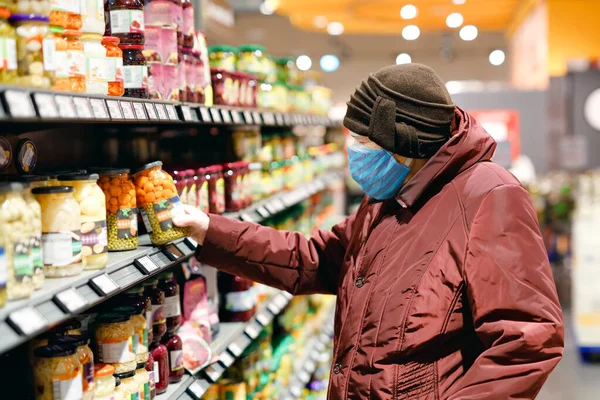 Oude oudere vrouw draagt een medisch masker, bescherming tegen pandemische coronavirus ziekte. 90 jaar gepensioneerde vrouwelijke dame duwen kar trolley om te winkelen in de supermarkt. Vrouw koopt eten en boodschappen — Stockfoto