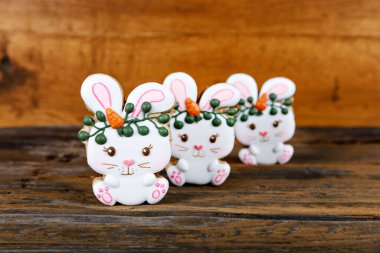 Kraliyet şekeriyle süslenmiş farklı Paskalya şekerli kurabiyelerin yakın çekimleri. Ahşap arka planda havuçlu tavşan. Tatlı bir hediye veya kartpostal.