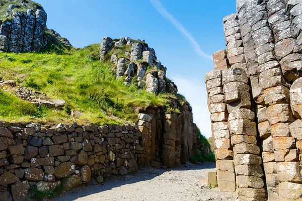 Camino de la Calzada del Paisaje de los Gigantes con un cielo azul en verano en Irlanda del Norte, Condado de Antrim. Patrimonio de la UNESCO. Es un área de columnas de basalto, el resultado de una antigua erupción de fisura volcánica — Foto de Stock