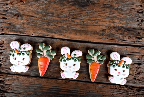 Primo piano di variazione di biscotti da zucchero pasquali diversi decorati con glassa reale. Coniglio coniglietto con carote su sfondo di legno. Delizioso regalo dolce o cartolina — Foto Stock