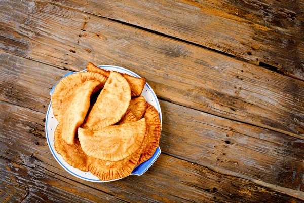 Cheburek fatti in casa ripieni di carne macinata e cipolle, cucina tradizionale caucasica e russa. Primo piano del gruppo di torte di pasta fritta fresca chiamato cheburek sul tavolo di legno. — Foto Stock