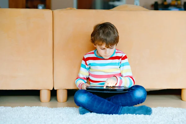 Um miúdo da escola a fazer trabalhos de casa com tablet. Leitura e aprendizagem escolar com computador, em busca de informações na internet. — Fotografia de Stock