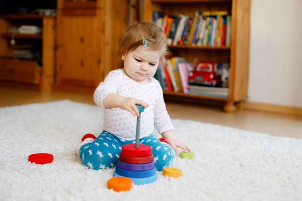 사랑스럽고 귀여운 작은 소녀가 교육용 나무 장난감을 가지고 집이나 보육원에서 놀고 있다. 화려 한 스택피라 밋 과 음악 장난감을 가진 아이들. 여러 가지 장난감을 가지고 재미있게 노는 행복 한 건강 한 자녀 — 스톡 사진