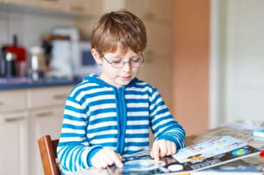 Gözlüklü sevimli küçük çocuk kitap okuyor. Sevimli mutlu okul çocuğu ve öğrenci mektup öğrenip okuyorlar. Komik çocuk anaokulu ödevi yapıyor. Eğitim kavramı