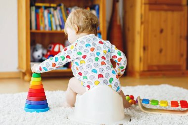 Klozetin üzerinde oturan 12 aylık küçük, şirin bebek kız çocuğunun yakın çekimi..