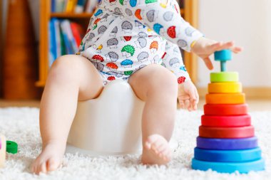 Klozetin üzerinde oturan 12 aylık küçük, şirin bebek kız çocuğunun yakın çekimi..