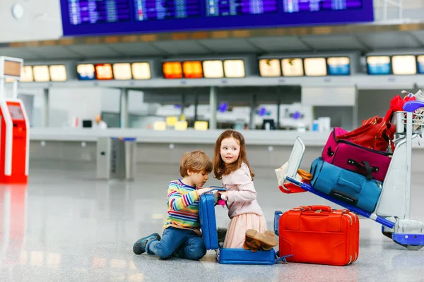 Havaalanındaki tatlı küçük kız ve oğlan. Yorgun çocuklar, yerde oturup rötarlı uçuş bekleyen kardeşler. Terminalde valizlerle birlikte oynayan çocuklar. Seyahat yaşam tarzı