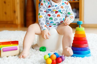 Klozetin üzerinde oturan 12 aylık küçük, şirin bebek kız çocuğunun yakın çekimi..