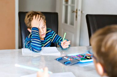 Corona ve Covin 19 salgın hastalığından karantina zamanında ödev yapan iki çalışkan okul çocuğu. Çocuklar, kardeşlerim kalemle yazıyor, evde kalıyorlar. Evde eğitim kavramı.