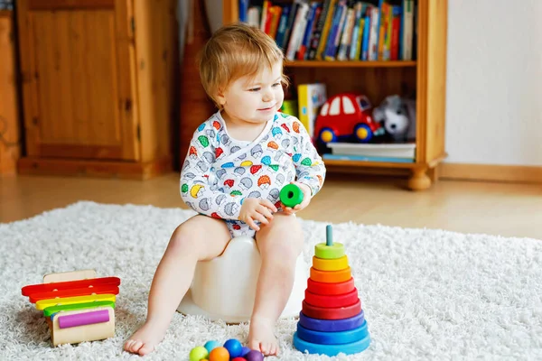 Closeup of cute little 12 months old toddler baby girl child sitting on potty.