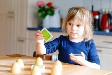 Salon oyunu oynayan sevimli küçük kız. Mutlu sağlıklı çocuk hafızasını eğitiyor, düşünüyor. Salgın Coronavirus covid karantina hastalığı sırasında çocuğun evde dinlenmesi ve eğitilmesi