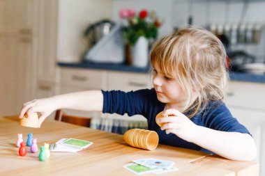 Salon oyunu oynayan sevimli küçük kız. Mutlu sağlıklı çocuk hafızasını eğitiyor, düşünüyor. Salgın Coronavirus covid karantina hastalığı sırasında çocuğun evde dinlenmesi ve eğitilmesi
