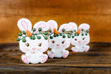 Kraliyet şekeriyle süslenmiş farklı Paskalya şekerli kurabiyelerin yakın çekimleri. Ahşap arka planda havuçlu tavşan. Tatlı bir hediye veya kartpostal.