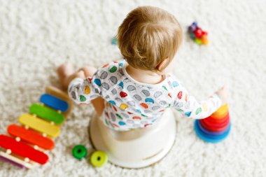 Klozetin üzerinde oturan 12 aylık küçük, şirin bebek kız çocuğunun yakın çekimi..