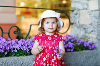 Pembe elbiseli, moda elbiseli, diz altı çoraplı ve şapkalı güzel küçük bir kız çocuğunun portresi. Renkli evin önünde poz veren mutlu sağlıklı bebek..