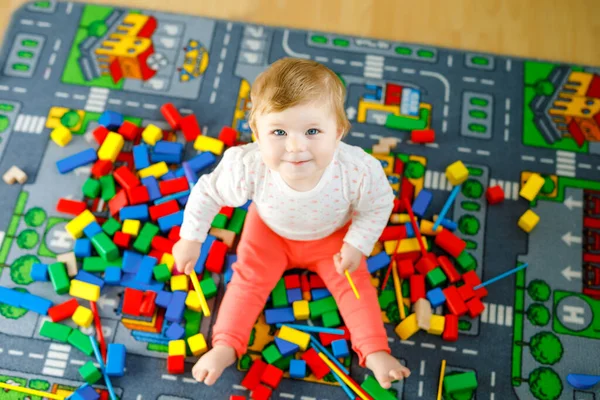 Adorable niña jugando con juguetes educativos. Feliz niño sano que se divierte con diferentes bloques de madera de colores en casa en la habitación doméstica. Bebé aprendizaje colores y formas — Foto de Stock