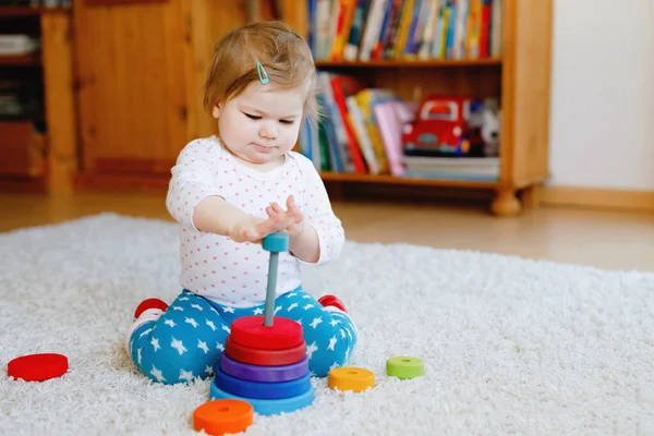 Adorável bonito linda menina brincando com brinquedos educativos de madeira em casa ou berçário. Criança com pirâmide pilha colorida e brinquedo de música. Criança saudável feliz se divertindo com brinquedos diferentes — Fotografia de Stock