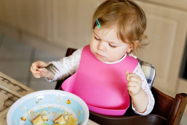 Entzückendes kleines Mädchen, das aus einem Löffel püriertem Gemüse und Püree isst. Ernährungs-, Kinder-, Ernährungs- und Personenkonzept — Stockfoto