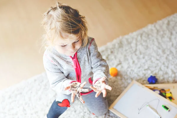 Tråkigt gråtande småbarn flicka lärande målning med filt tips pennor. Ett litet barn som ritar på händer och kläder. Arga barn i hysterisk kris som föräldrar skälla med dotter för smutsiga händer. — Stockfoto