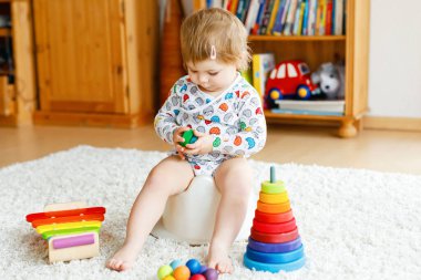 Klozetin üzerinde oturan 12 aylık küçük, şirin bebek kız çocuğunun yakın çekimi..