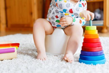 Klozetin üzerinde oturan 12 aylık küçük, şirin bebek kız çocuğunun yakın çekimi..