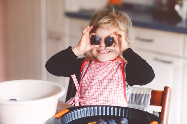 かわいい幼児の女の子自宅で梅のパイを焼く。家庭の台所でケーキのための梅を支援し、準備幸せな笑顔の子供。健康的な自家製食品. — ストック写真