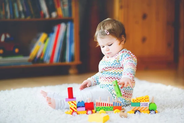 Liten flicka leker med pedagogiska träleksaker hemma eller på dagis. Småbarn med färgglada tåg. Barn som har roligt med olika leksaker. Ensam unge under koronaviruspandemisk karantän — Stockfoto