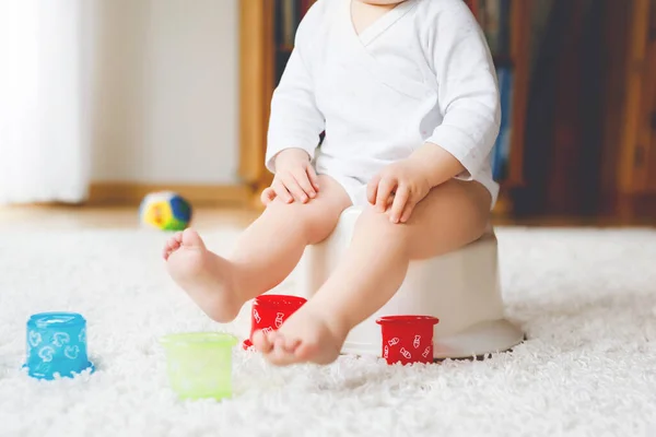 Lazımlığın üzerinde oturan küçük, tatlı, yaşlı, küçük kız bebek. Çocuk eğitim oyuncağı ve tuvalet eğitimi konseptiyle oynuyor. Bebek öğrenme, gelişme adımları. Yüzü yok, tanınmayan biri.. — Stok fotoğraf