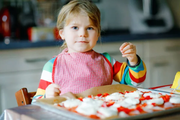 Adorable little toddler girl making italian pizza at home. Cute happy child having fun in home kitchen, indoors. Kid, preschooler helping and preparing healthy meal — Stock Photo, Image