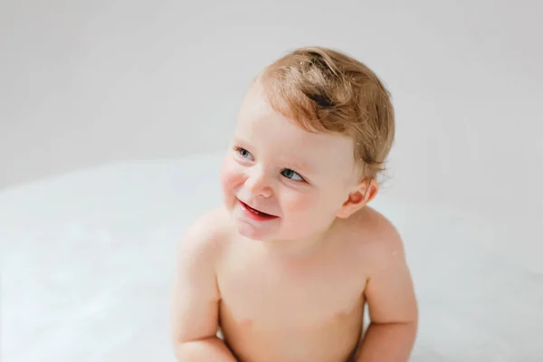 Roztomilé rozkošné dítě koupající se ve vaně doma. Šťastný zdravý chlapec nebo dívka hrát, cákání a bavit se během koupání. Hygiena a koncepce čištění pro kojence. — Stock fotografie