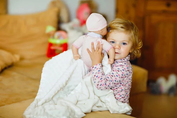 Schattig schattig klein peutermeisje dat met een pop speelt. Gelukkig gezond baby kind hebben plezier met rollenspel, spelen moeder thuis of kinderkamer. Actieve dochter met speelgoed. — Stockfoto