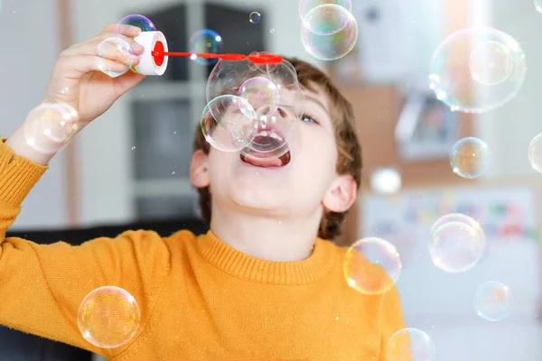 Menino da escola feliz brincando com bolhas de sabão em casa. O miúdo está a divertir-se. Criança brincando na escola, fazendo experiência — Fotografia de Stock