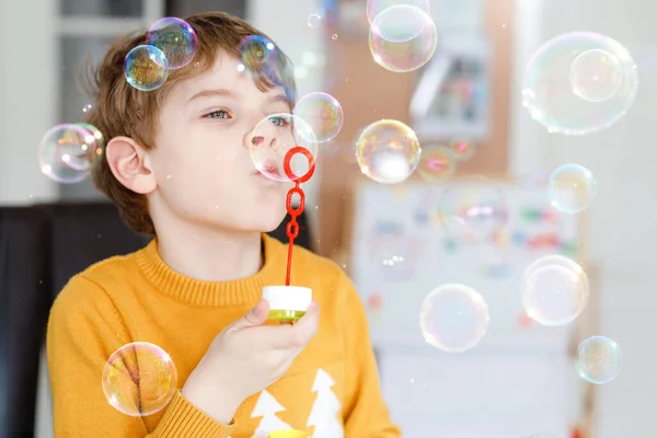 Menino da escola feliz brincando com bolhas de sabão em casa. O miúdo está a divertir-se. Criança brincando na escola, fazendo experiência — Fotografia de Stock