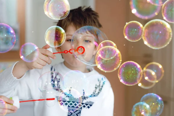 Glad liten skolpojke leker med såpbubblor hemma. Grabben har roligt. Leka barn i skolan, göra experiment — Stockfoto