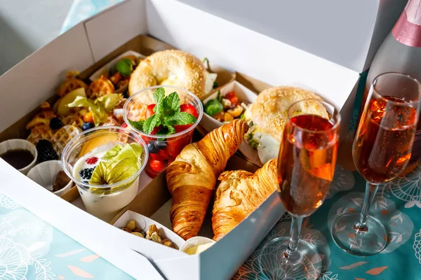 Colazione in una scatola per passare dal ristorante chiuso a causa del blocco del virus corona. Bagel freschi, cornetti, bacche, insalata e verdure per un pranzo romantico. Cibo per andare a fare picnic. — Foto Stock