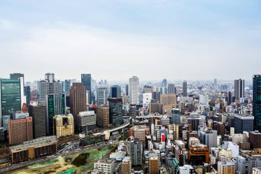 OSAKA, JAPONYA - 18 Mayıs 2015: Japonya 'daki Osaka şatosunun tepesinden gökdelenler, otobanlar ve parklarla Osaka şehrinin ufuk çizgisine bakın. Osaka ilinin başkentidir..