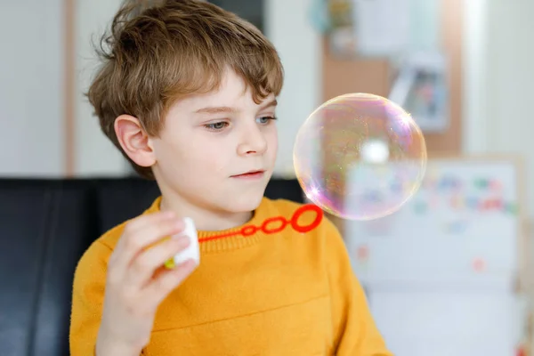 Menino da escola feliz brincando com bolhas de sabão em casa. O miúdo está a divertir-se. Criança brincando na escola, fazendo experiência — Fotografia de Stock