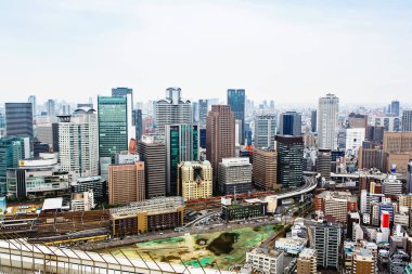 OSAKA, JAPONYA - 18 Mayıs 2015: Japonya 'daki Osaka şatosunun tepesinden gökdelenler, otobanlar ve parklarla Osaka şehrinin ufuk çizgisine bakın. Osaka ilinin başkentidir..