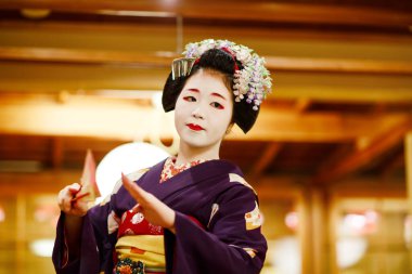 KYOTO, JAPONYA - 18 Mayıs 2015: Japon geleneksel dansını gösteren Maiko çırağı. Maiko bir çırak geyşa. Maikos ozashiki 'deki ziyaretçiler için şarkı söylüyor, shamisen çalıyor veya enstrümanlar çalıyor.