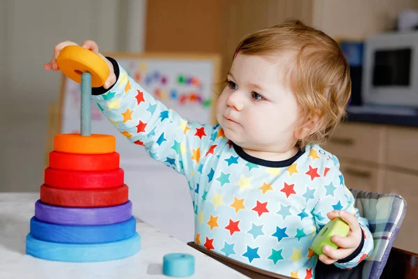 Cute beautiful little baby girl playing with educational toys at home or nursery, indoors. Happy healthy child having fun with colorful wooden rainbow toy pyramid. Kid learning different skills. — Stock Photo, Image