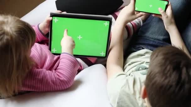 Παιδί αγόρι και κοριτσάκι gaming ή χρησιμοποιώντας τα μέσα κοινωνικής δικτύωσης στο κινητό τηλέφωνο και tablet με chroma κλειδί φόντο. Δύο παιδιά που κατέχουν smartphone και laptop με πράσινη οθόνη για το εμπόριο, νέα εφαρμογή — Αρχείο Βίντεο
